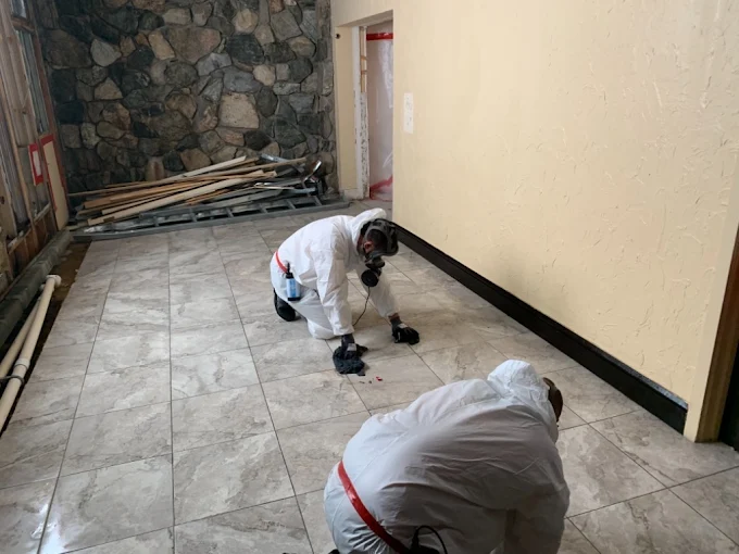 workers scrub a tile floor in preparation for hazardous material removal