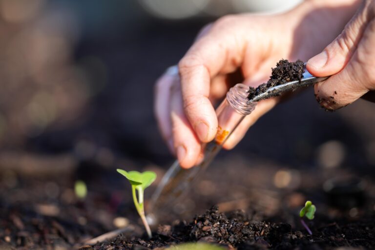 scraping soil into a test tube for analysis